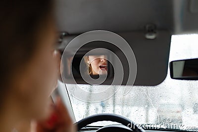 A young girl puts make-up in the car. Stock Photo