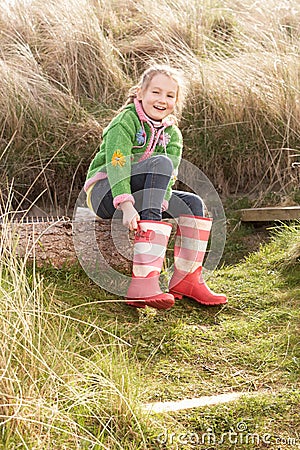 Young Girl Putting On Wellington Boots Stock Photo