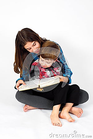 Young Girl Reads Bible To Her Little Brother Stock Photo