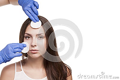 A young girl at the reception at the dermatologist. Cleaning with cotton pads. The doctor in blue gloves. Perfect skin. Stock Photo