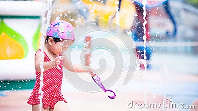 Young girl in red bathing suit was playing in fountain courtyard happily. Asian child were happy and laughed brightly. Stock Photo