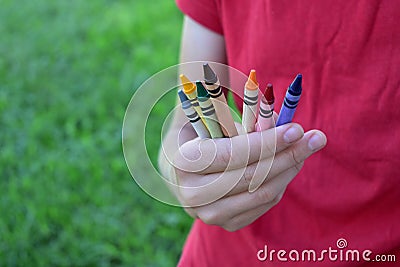A young girl with a red shirt holding crayons Stock Photo