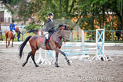 Young girl riding bay horse on show jumping Stock Photo