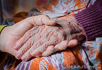 Young girl's hand touches and holds an old woman hand Stock Photo