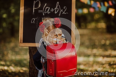 Young girl in school uniform writing on a board outdoor. Back to school Stock Photo