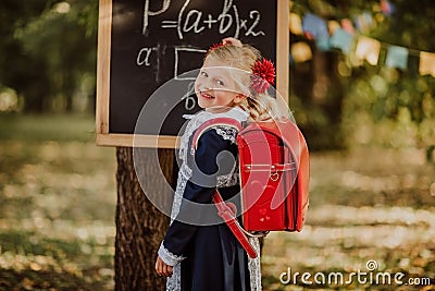 Young girl in school uniform writing on a board outdoor. Back to school Stock Photo