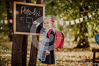 Young girl in school uniform writing on a board outdoor. Back to school Stock Photo