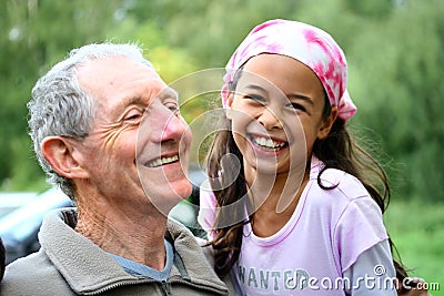 A young girl sharing a joke with her grandfather Stock Photo