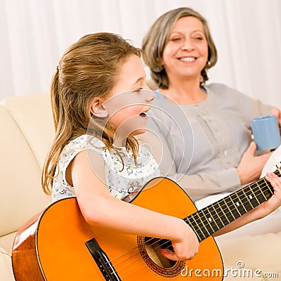 Young girl sing play guitar to grandmother Stock Photo