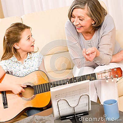 Young girl sing play guitar to grandmother Stock Photo