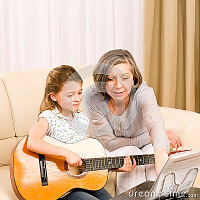 Young girl sing play guitar to grandmother Stock Photo