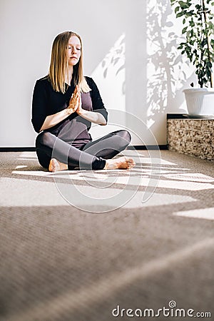 Young girl sitting on the floor in the pose of meditation Stock Photo