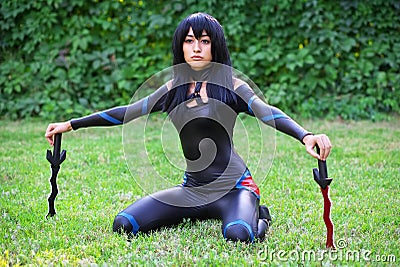 Young girl sitting on the grass and holding two dirks. Stock Photo