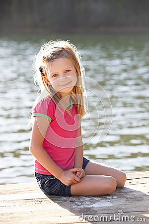 Young girl sitting by lake Stock Photo