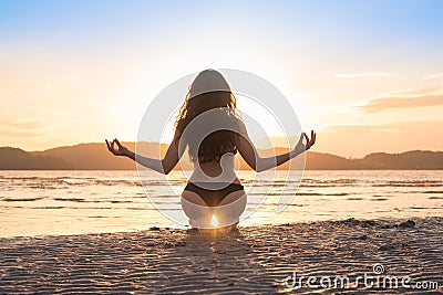 Young Girl Sitting Lotus Pose On Beach At Sunset, Beautiful Woman Practicing Yoga Summer Vacation Meditation Seaside Stock Photo