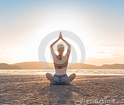 Young Girl Sitting Lotus Pose On Beach At Sunset, Beautiful Woman Practicing Yoga Summer Vacation Meditation Seaside Stock Photo