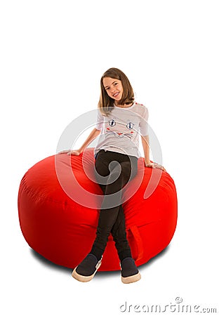 Young girl sitting on round shape red beanbag chair Stock Photo