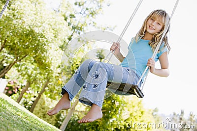 Young girl sitting on swing smiling Stock Photo