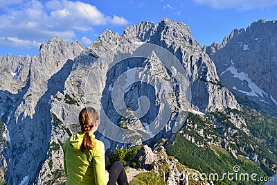 Young girl is sitting on the top of the mountains, enjoying beautiful view on the mountain range Kaisergebirge, Austria. Editorial Stock Photo