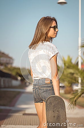 Young girl with a skateboard posing on the street Stock Photo