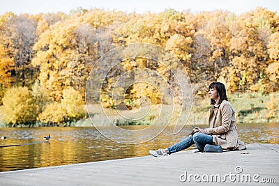 A young girl sketching near a lake in the autumn forest. Stock Photo