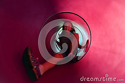 Young Girl Sliding Down Tube Slide Stock Photo