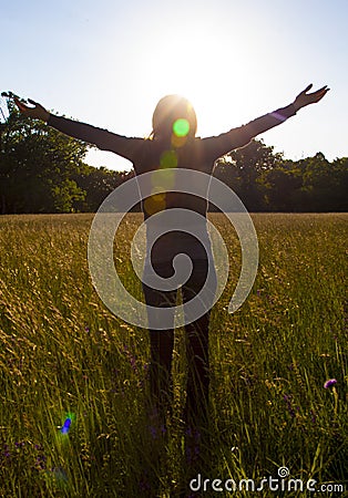 Young girl spreading hands with joy and inspiration facing the sun,sun greeting Stock Photo