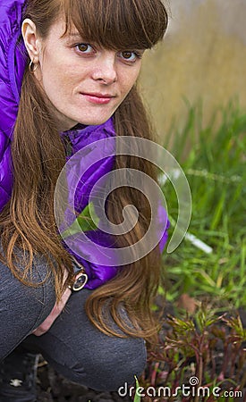 The young girl squatted next to the seedlings in her garden Stock Photo