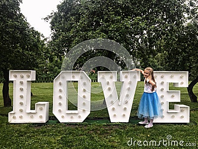 Young girl standing at love neon letters in a park Stock Photo