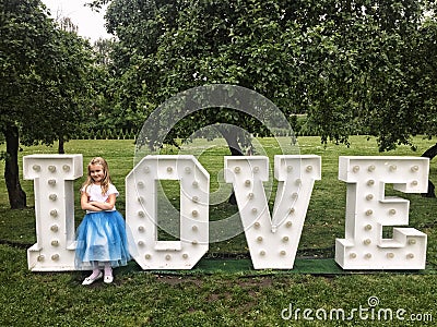 Young girl standing at love neon letters in a park Stock Photo