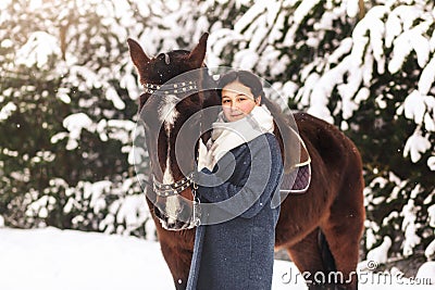 Young girl stands with a horse in the winter outdoors Stock Photo
