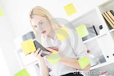 A young girl stands with a phone in her hands near a transparent Board with stickers. Stock Photo