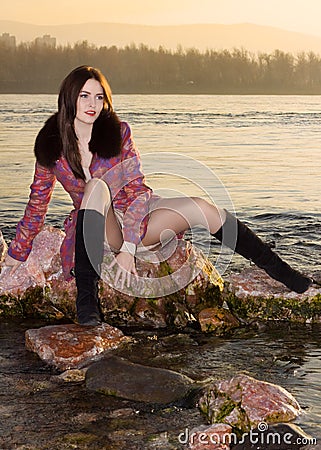 Young girl on stones near a rural river Stock Photo