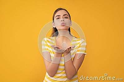 young girl in summer striped tshirt on yellow background. blow kiss Stock Photo