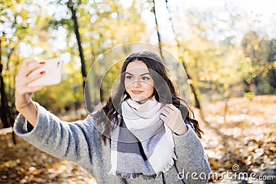 Young girl takes a selfie on the backgroung autumn park Stock Photo