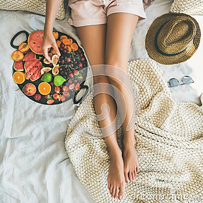 Young girl taking fig from tray full of fresh fruits Stock Photo