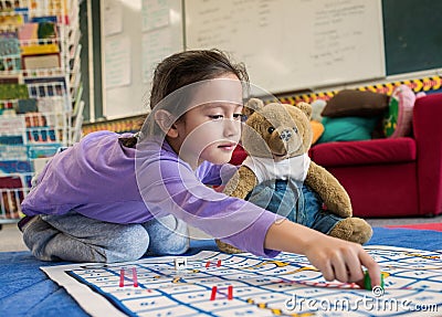 Young Girl and Teddy Playing Snakes and Ladders Stock Photo