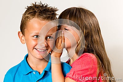 Young girl telling secret to young boy Stock Photo