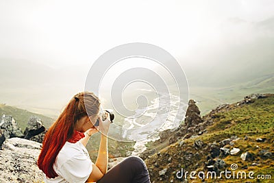 A young girl traveler takes pictures of a summer mountain landscape. Elbrus region, Russia. Woman Emancipation Concept Stock Photo