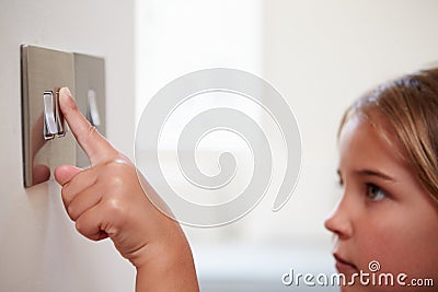 Young Girl Turning Off Light Switch Stock Photo