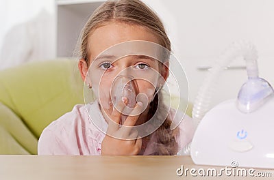 Young girl using a nebulizer inhaler device with mist shooting out of the mouthpiece Stock Photo