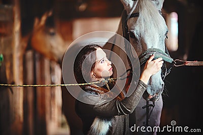 A young girl in a village stables saddles her horse. Stock Photo