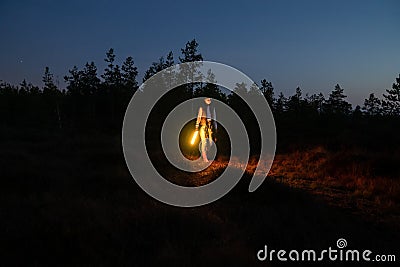 Young girl walk countryside at night hold led lamp to highlight pathway to camp or car after hiking Stock Photo
