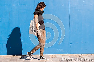 Young girl walking on street with blue wall in background. Stock Photo