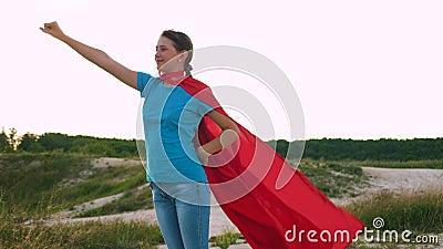 Young girl walks in a red cloak expression of dreams. girl dreams of becoming a superhero. beautiful girl superhero Stock Photo