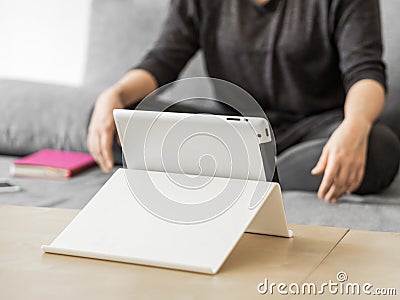 Young girl watching lessons on a tablet sitting on gray sofa. Business woman on quarantine. Online education concept Stock Photo