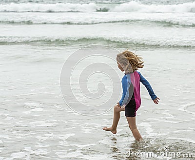 Young girl wearing a colorful swimming suit having fun splashing at the beach Stock Photo