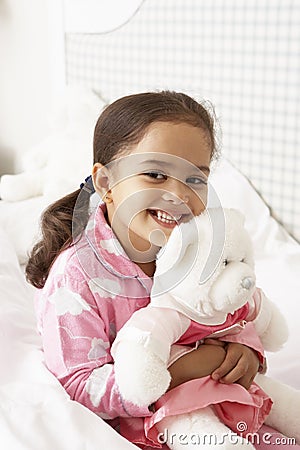 Young Girl Wearing Pajamas In Bed With Cuddly Toy Stock Photo