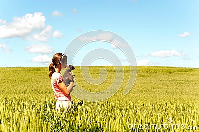 Young girl in wheat field holding dog contemplating the nature Stock Photo