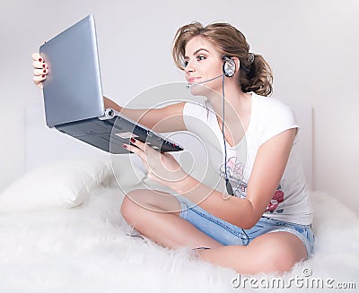 Young girl witn silver laptop and skype headset Stock Photo